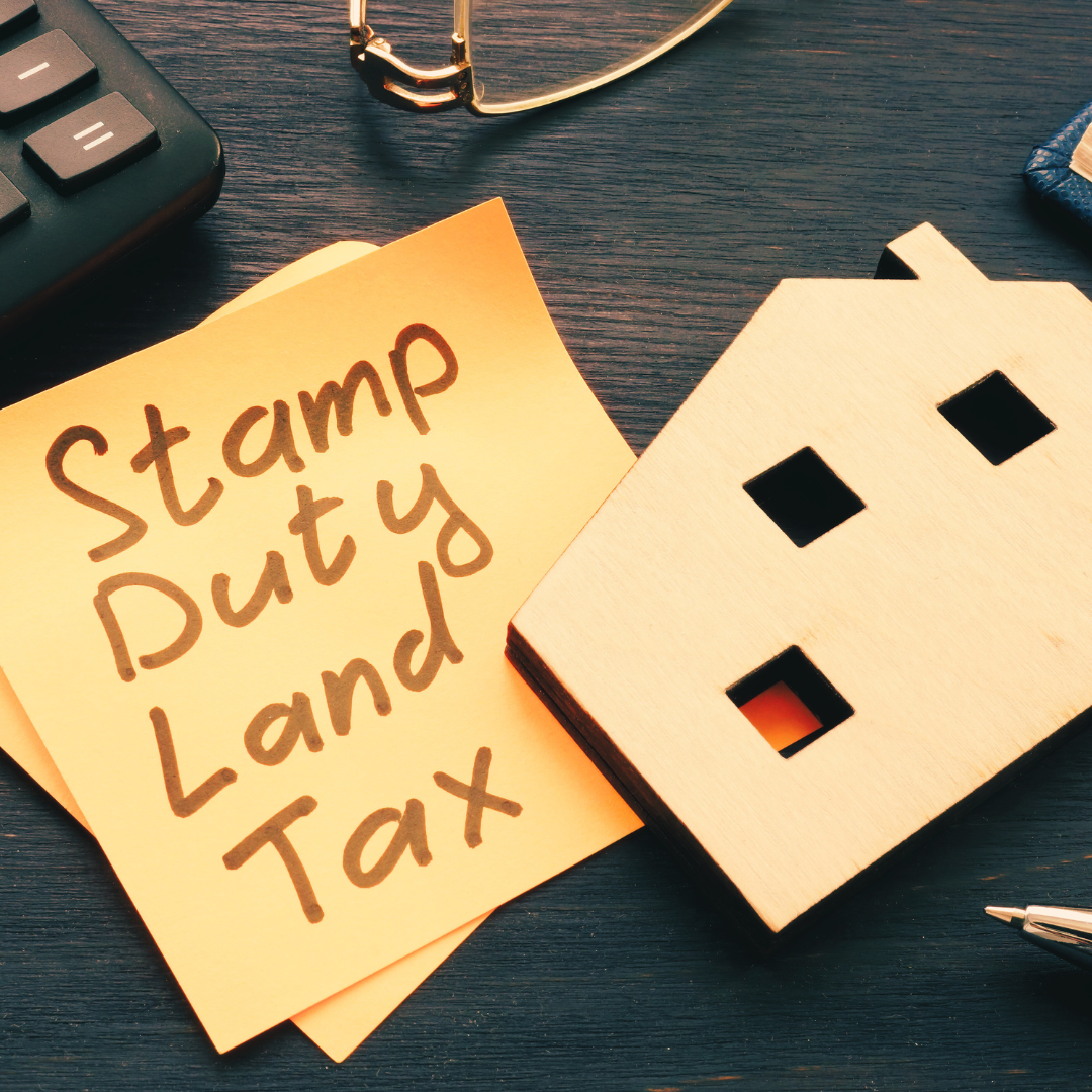 This is a photo of a wooden house and a post it note that says Stamp Duty Land Tax